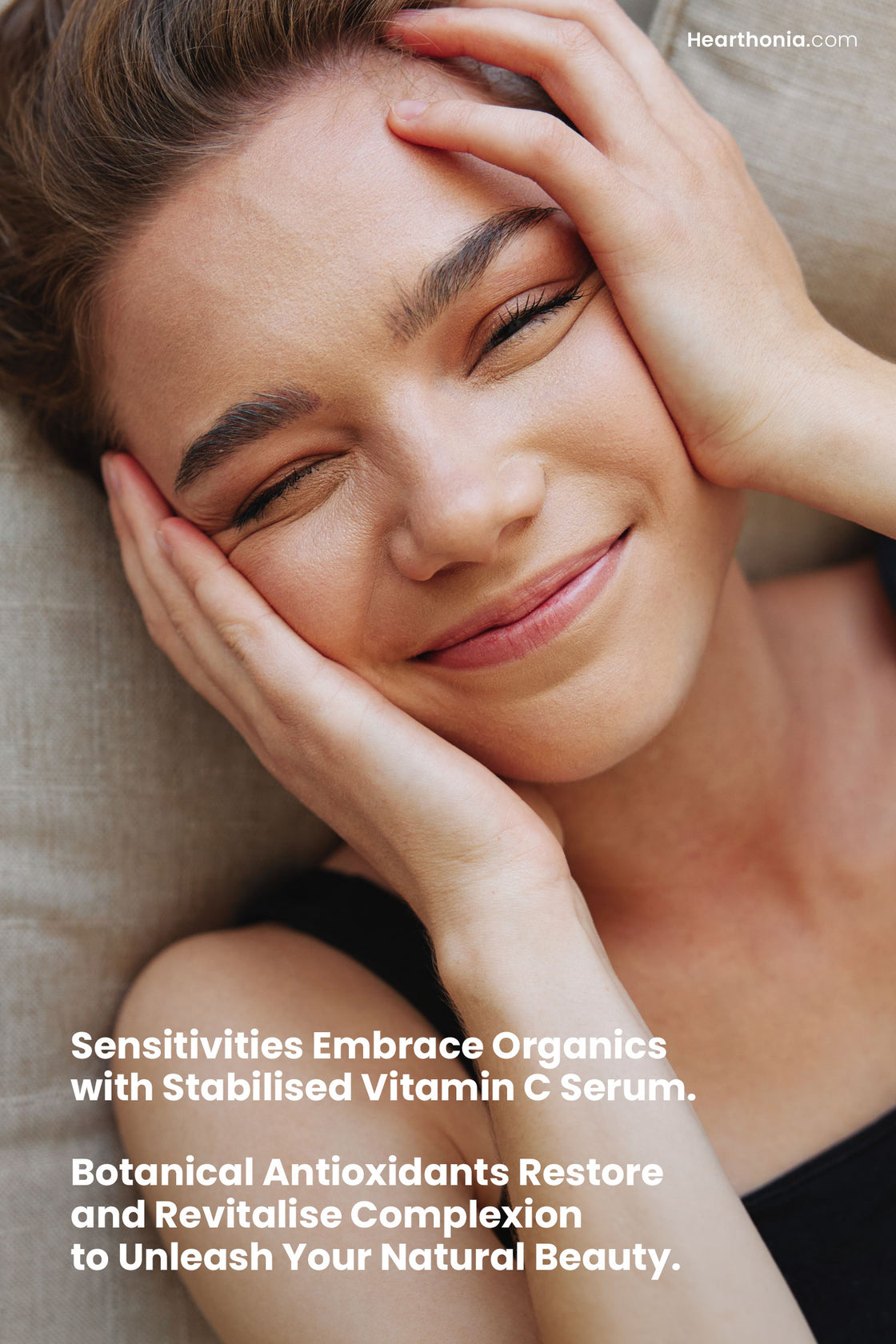 Smiling young woman, happily touching her face, with text appearing "Sensitivities embrace organics with stabilised vitamin c serum. Botanical antioxidants restore and revitalise complexion to unleash your natural beauty".