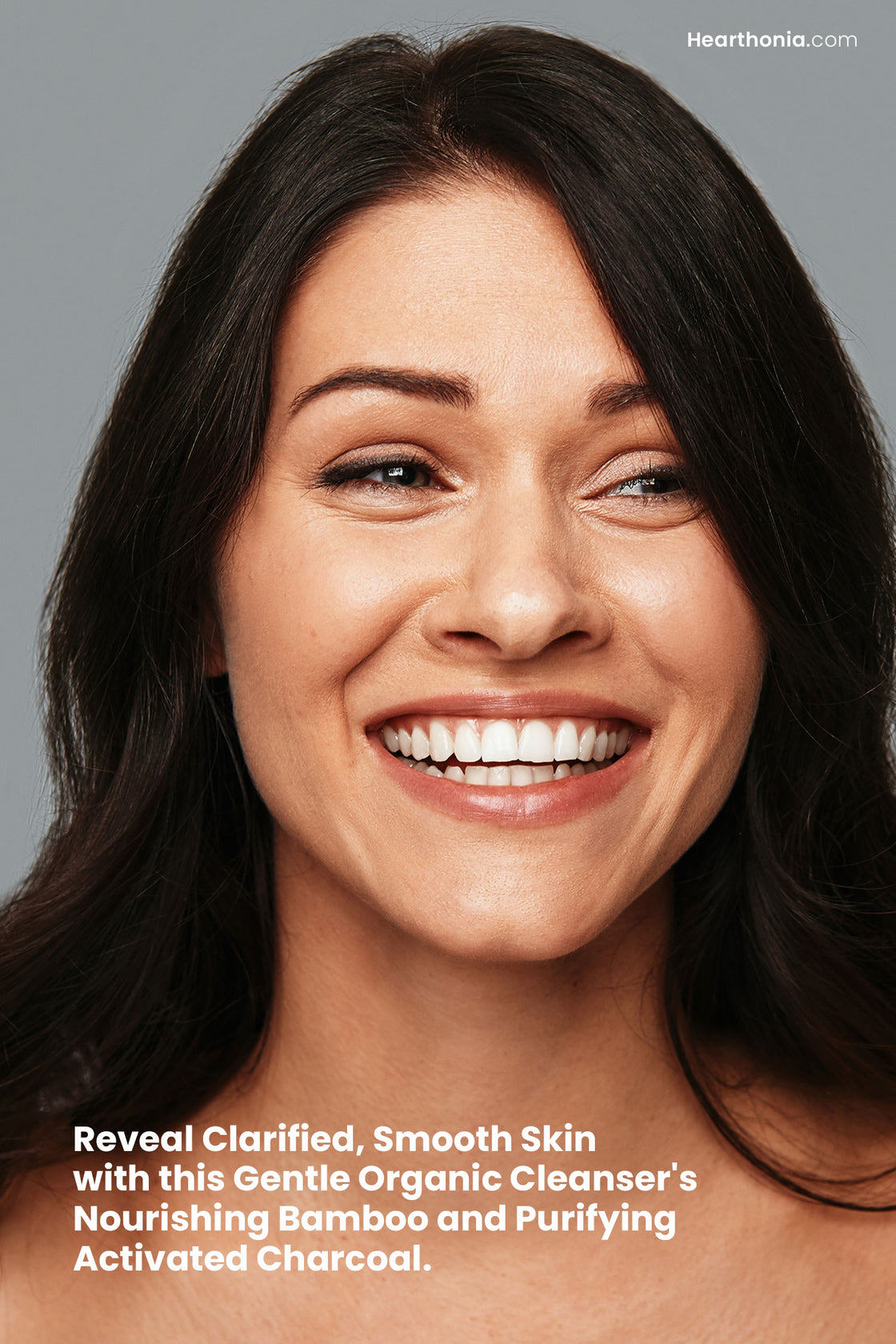 Smiling woman showcasing refreshed facial skin with text stating "reveal clarified, smooth skin with this gentle organic cleanser's purifying activated charcoal".