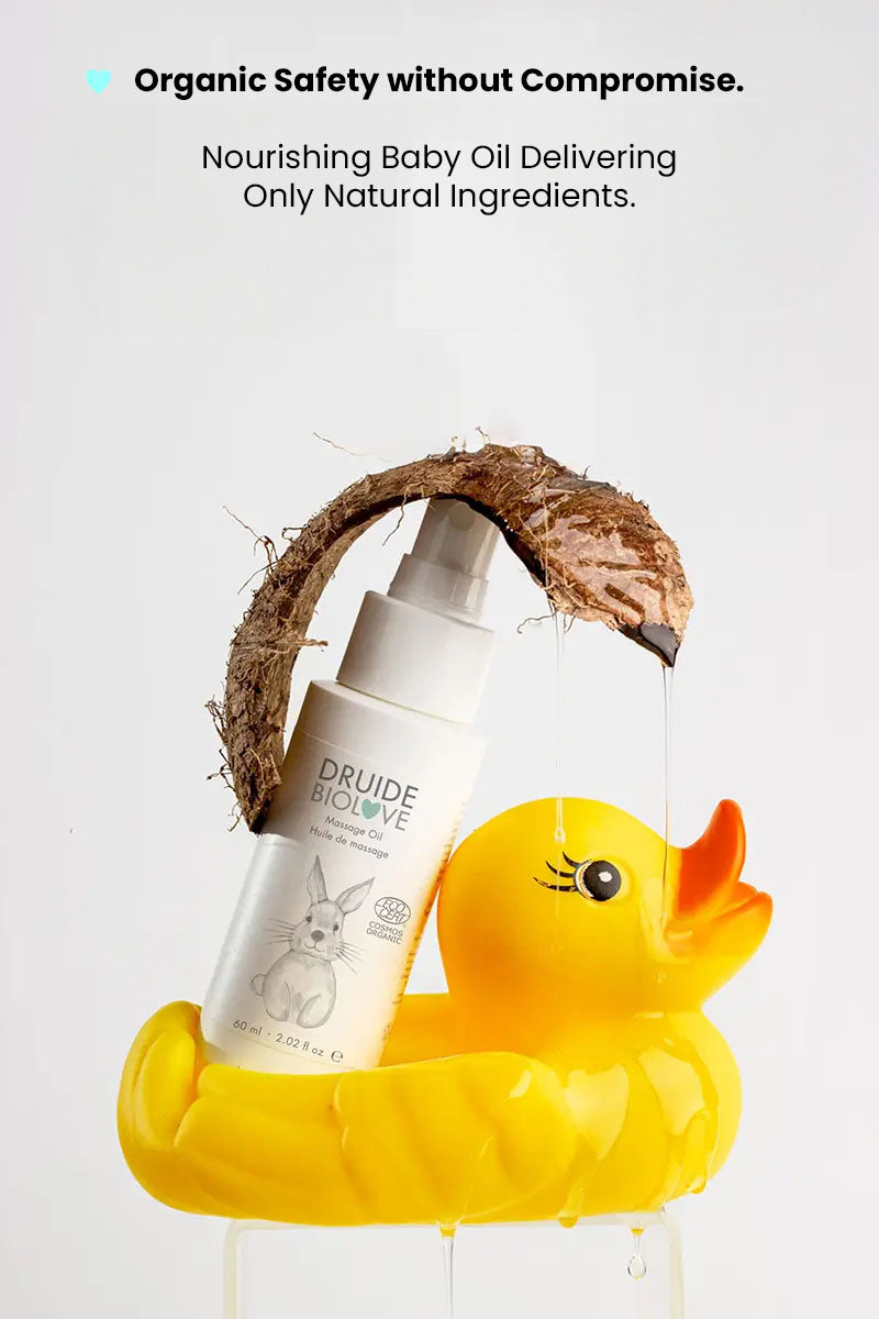 Druide Biolove organic massage oil 
dispenser stacked on a yellow rubber duck toy with a coconut piece above it showing opaque oil dripping.