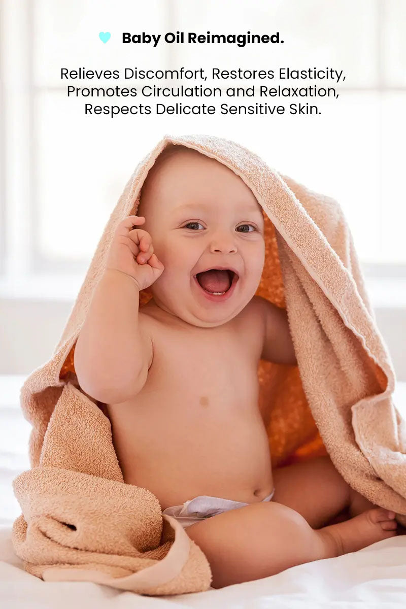 happy baby smiling after a massage with a towel on head and text reading "baby oil reimagined, relieves discomfort, restores elasticity, promotes circulation and relaxation, respects delicate sensitive skin".