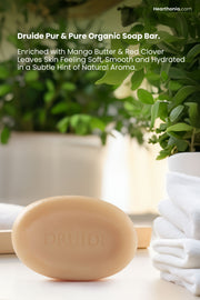 Druide Pur and Pure natural soap bar   
for Face & Body propped on a white surface next to a bathtub surrounded by green plants and bathed in natural sunlight with text reading 
