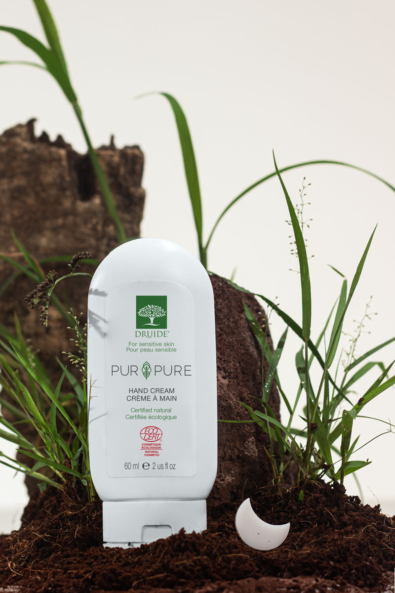 Druide Pur and Pure organic Hand Cream dispenser shown in natural background of soil and grass.