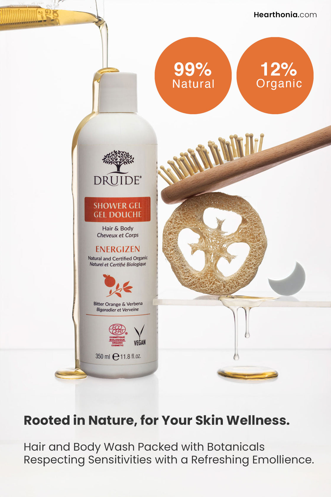 Druide organic hair and body wash, in its flip-top dispenser standing on a clear counter next to a loofah and wooden hairbrush on a separate shelf. The image shows the gel pouring out of a beaker while highlighting its 99% natural and 12% organic constitution with text reading "rooted in nature for your skin wellness".